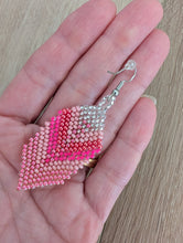 Laden Sie das Bild in den Galerie-Viewer, Pink beaded earrings held in a hand on a wooden surface
